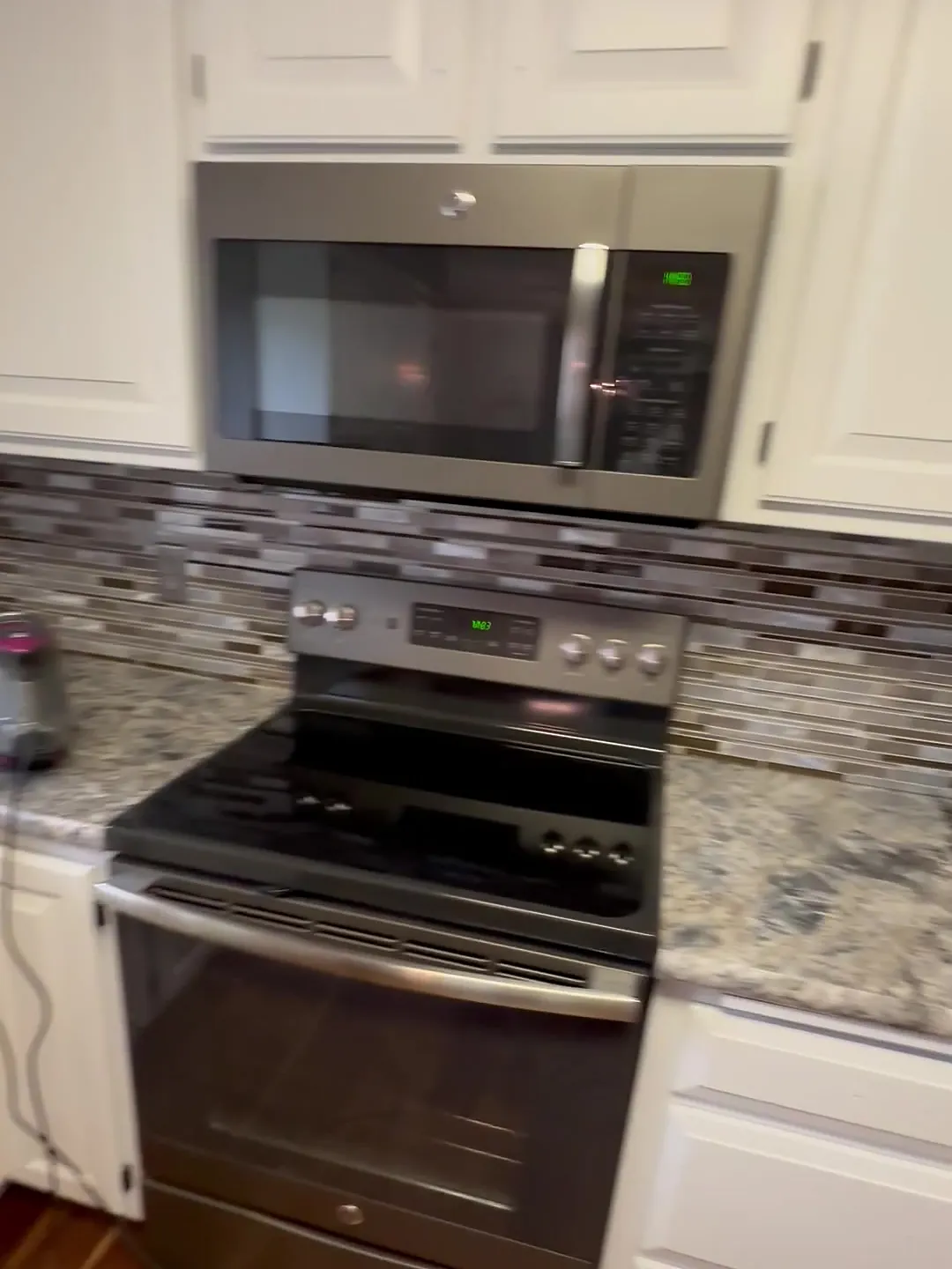 Close view of white painted cabinets around the range and microwave in the Andover kitchen, White Dove.