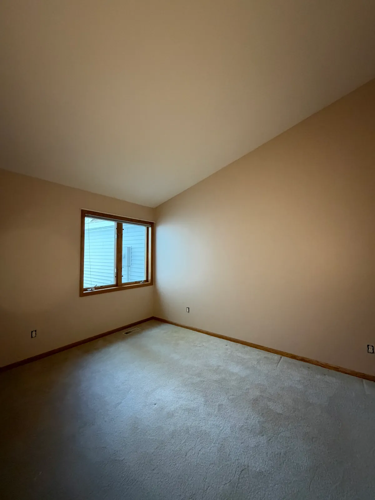 The same Anoka townhome bedroom after painting, walls in Lightweight Beige, wood window left as it was.