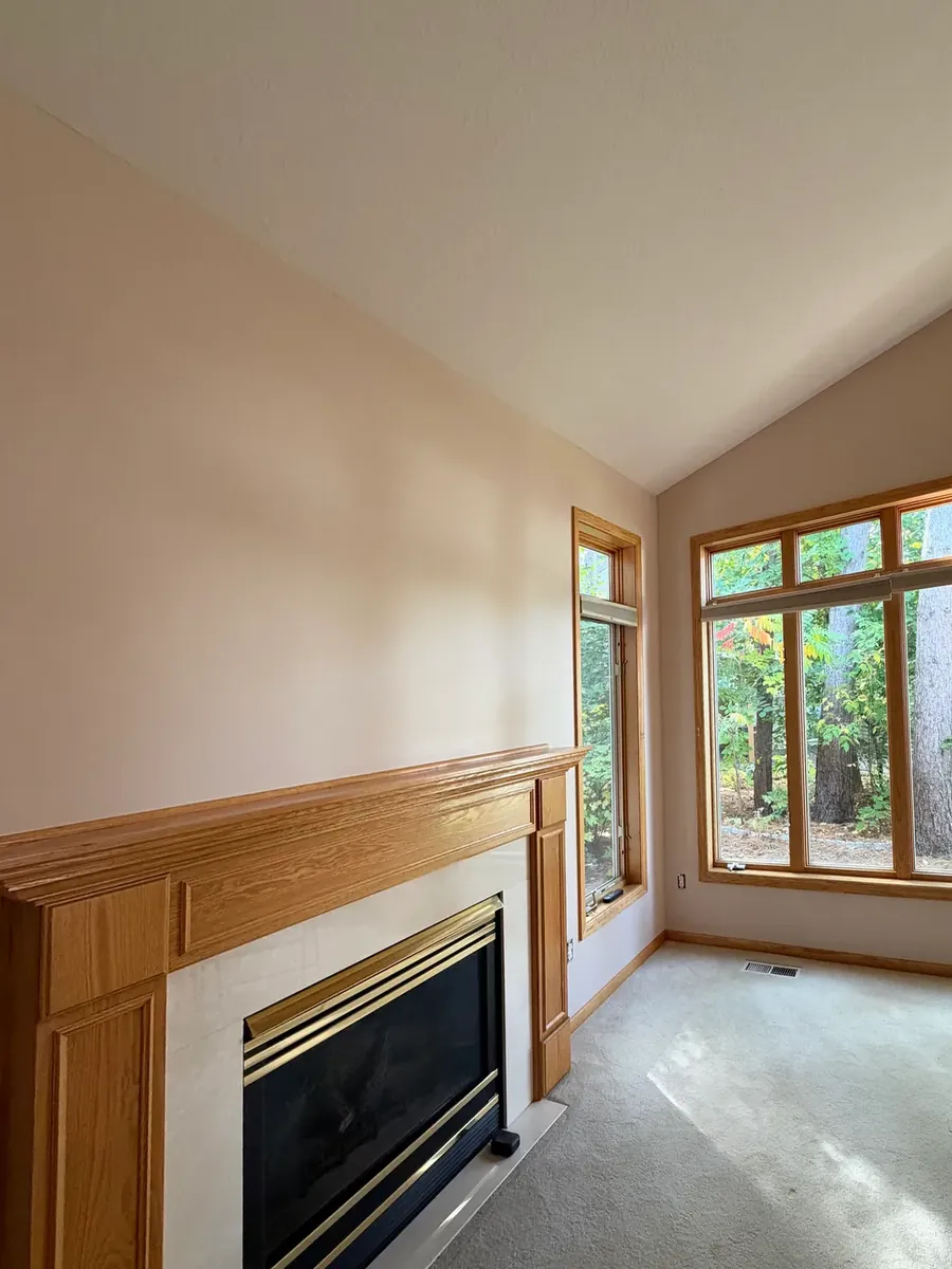 The same Anoka townhome living room after painting in Lightweight Beige, fireplace and wood windows left as they were.