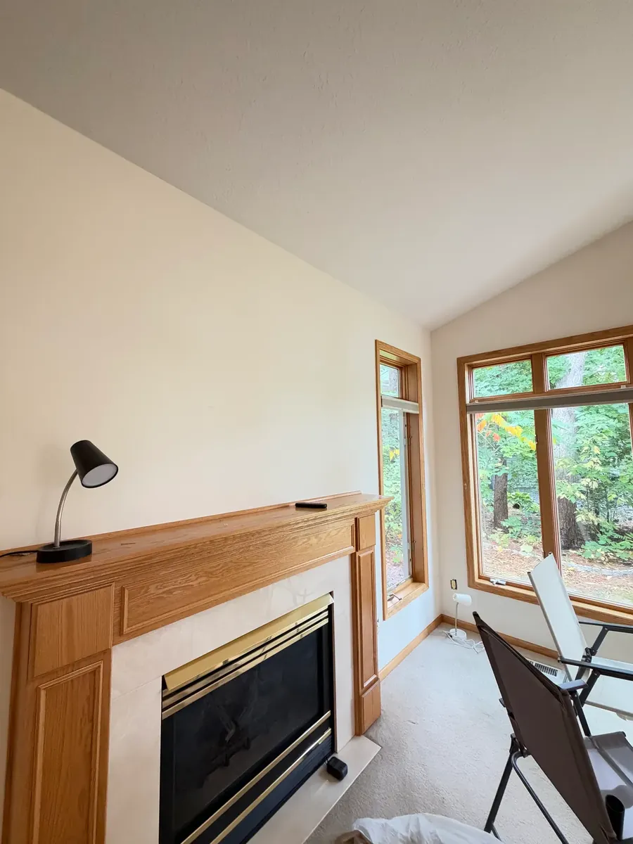 Anoka townhome living room before painting, with the fireplace and the corner windows.