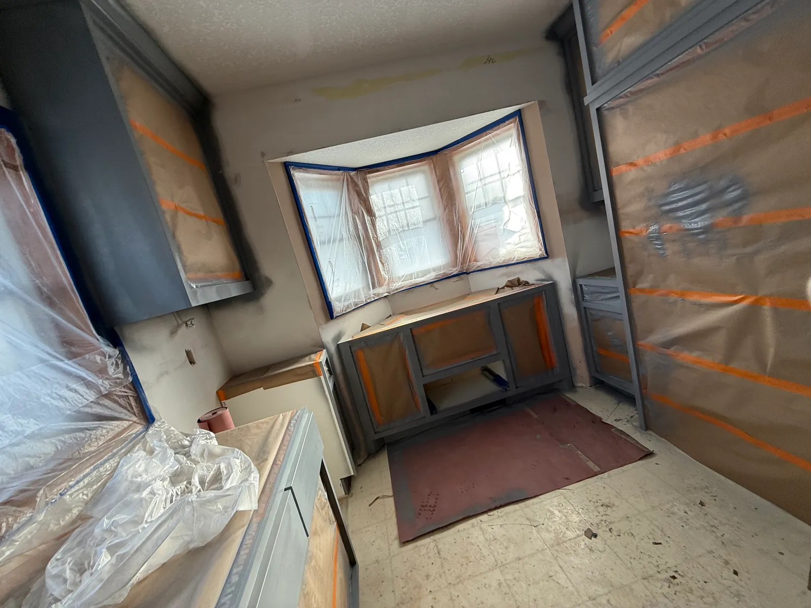 Coon Rapids kitchen cabinet boxes sprayed gray on site, with the rest of the kitchen still masked.