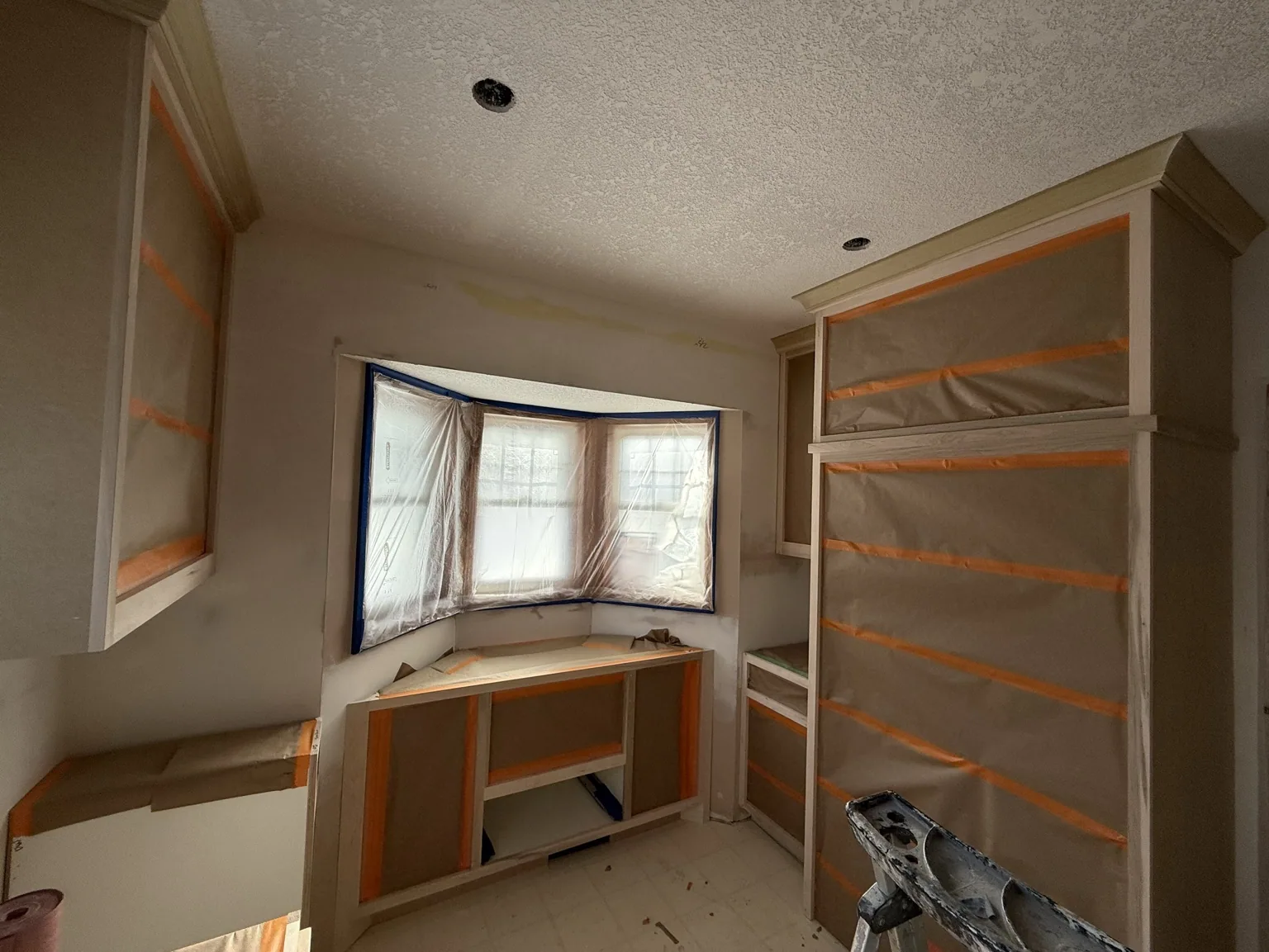 Coon Rapids kitchen masked off with paper and plastic for spraying, doors off, by the bay window.