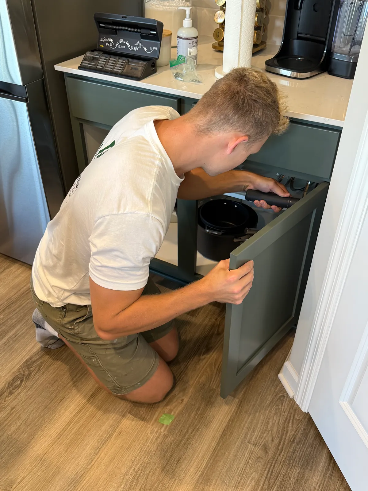 Adjusting a hinge on a Pewter Green base cabinet door after reinstalling it in the St. Michael kitchen.