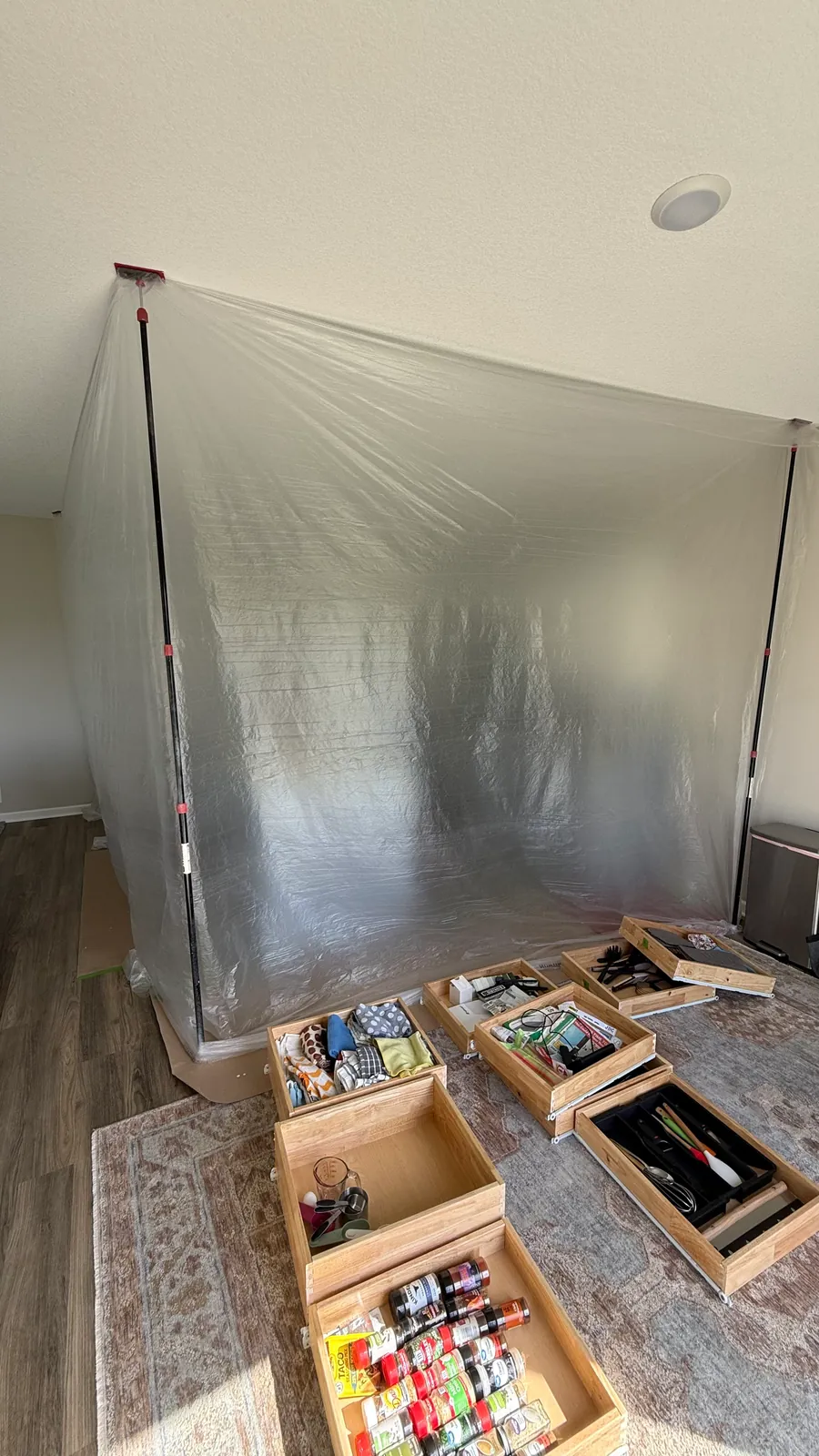 Plastic dust containment wall set up at the edge of a kitchen in St. Michael, with cabinet drawers pulled out on the floor in front of it.