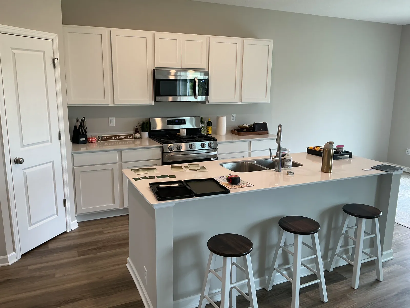 Kitchen in St. Michael before the base cabinets and island were refinished, with white base cabinets, a white island, and white upper cabinets.
